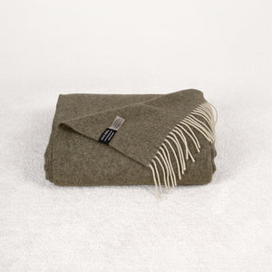 Khaki green cashmere blanket folded on a soft white rug