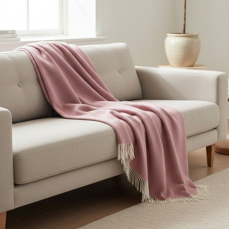 Beige sofa with a pink throw blanket in a cozy living room setting.