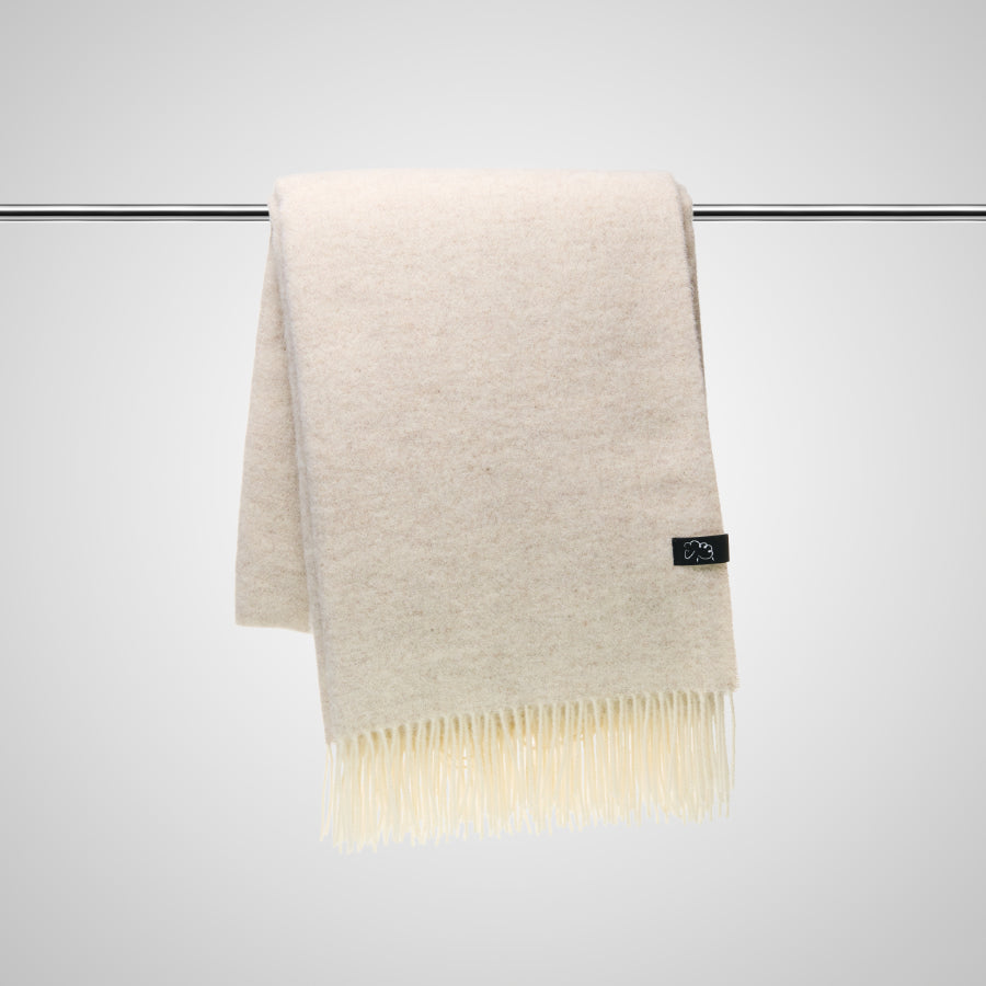 Beige folded blanket with a brand label on a white background