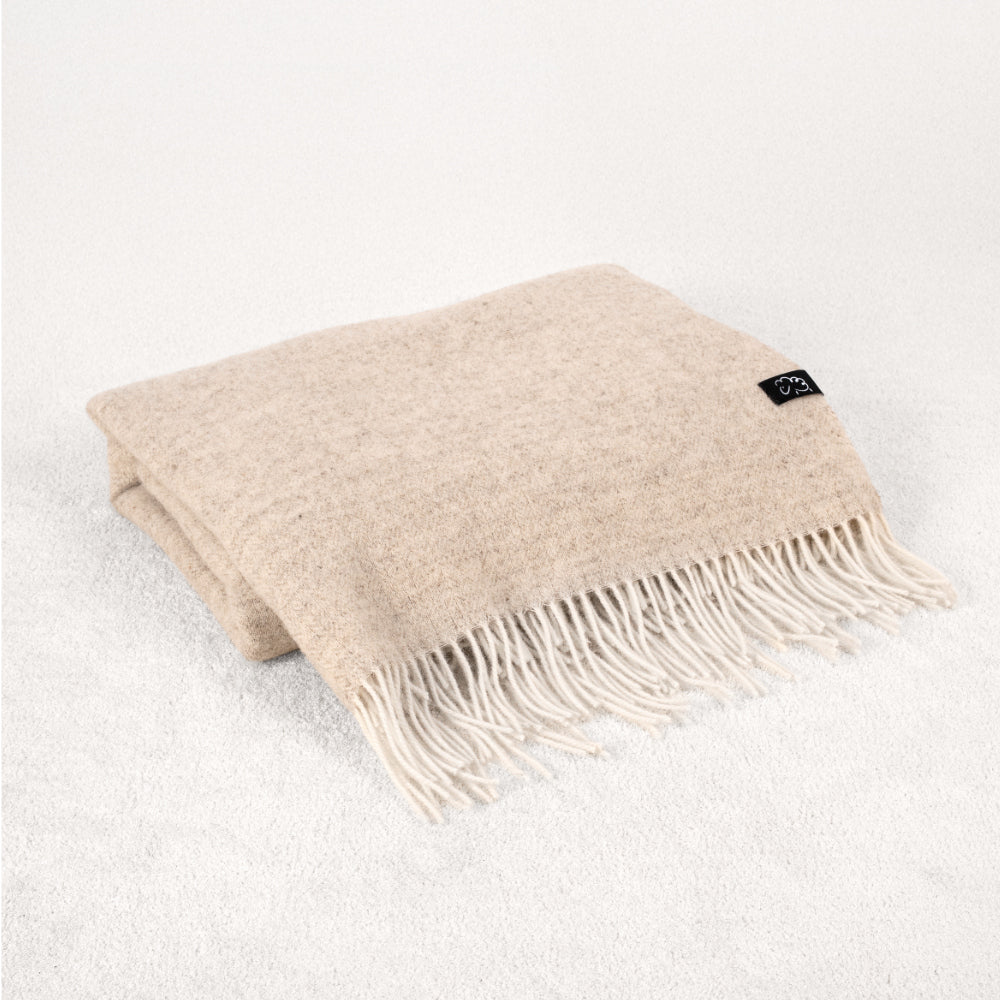 Beige throw blanket with fringes on a white background