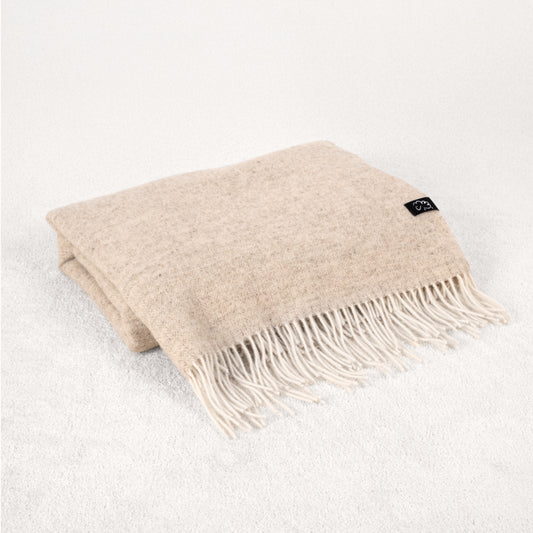Beige throw blanket with fringes on a white background