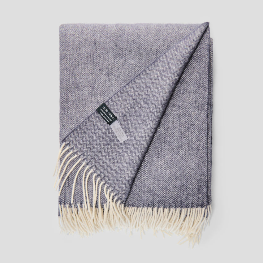 Gray plaid blanket with white fringe on a light gray background