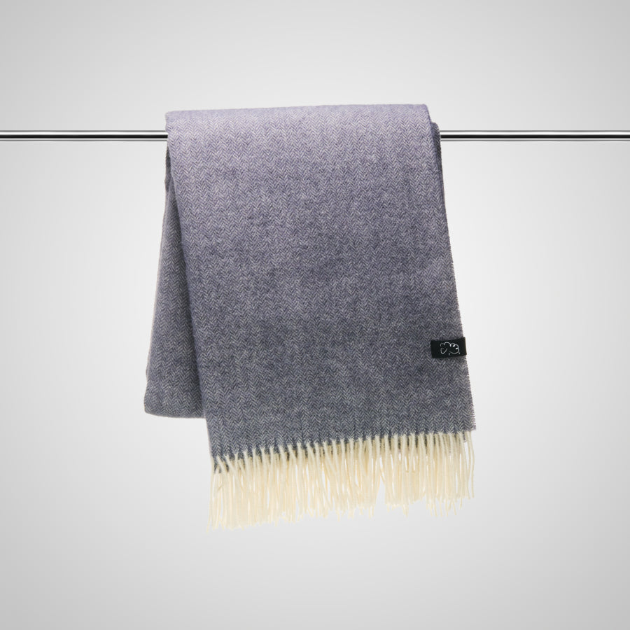 Deep dark grey throw with white fringe on a bar against a light gray background