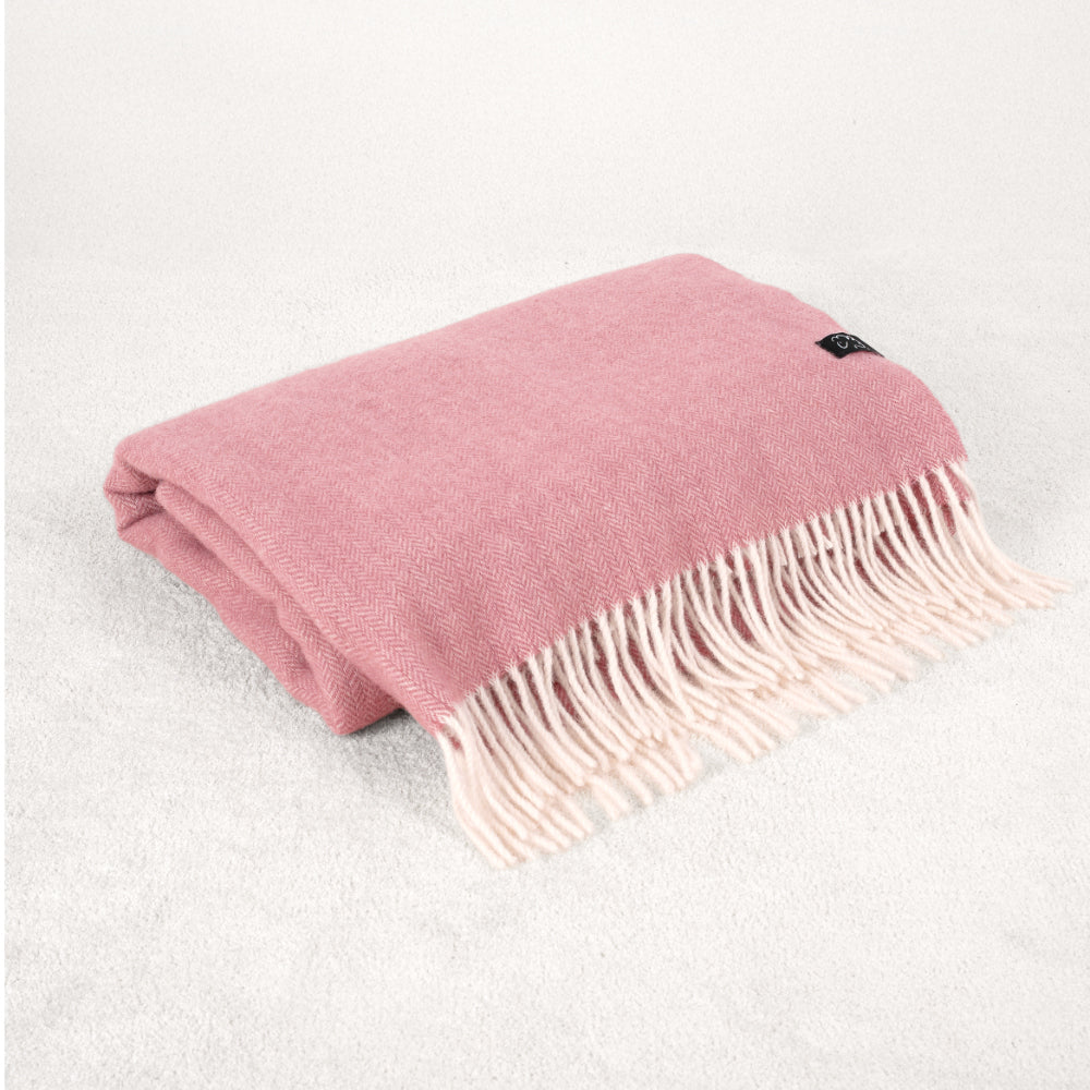 Rose Pink wool blanket throw with white fringe on a soft white rug