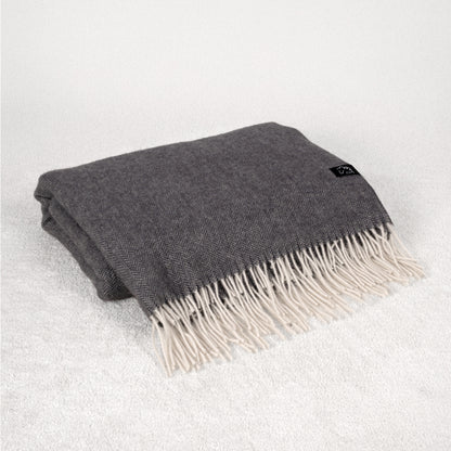 Gray blanket with white fringe on a light gray background