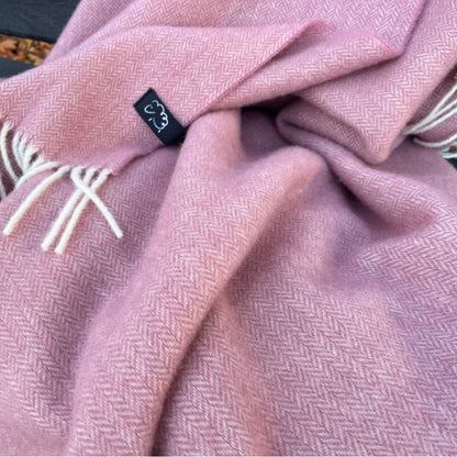 Pink wool blanket with a textured pattern and a visible brand tag.